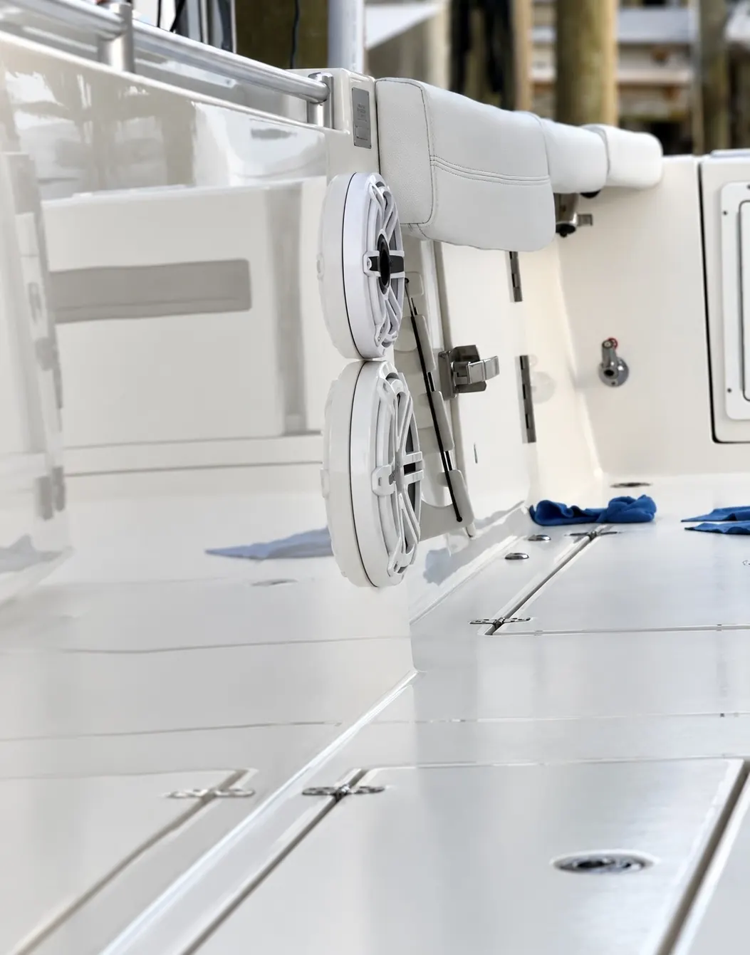 A white cockpit with a mirror finish: deck hatches, two speakers under a folded seat, microfibre towels on the deck